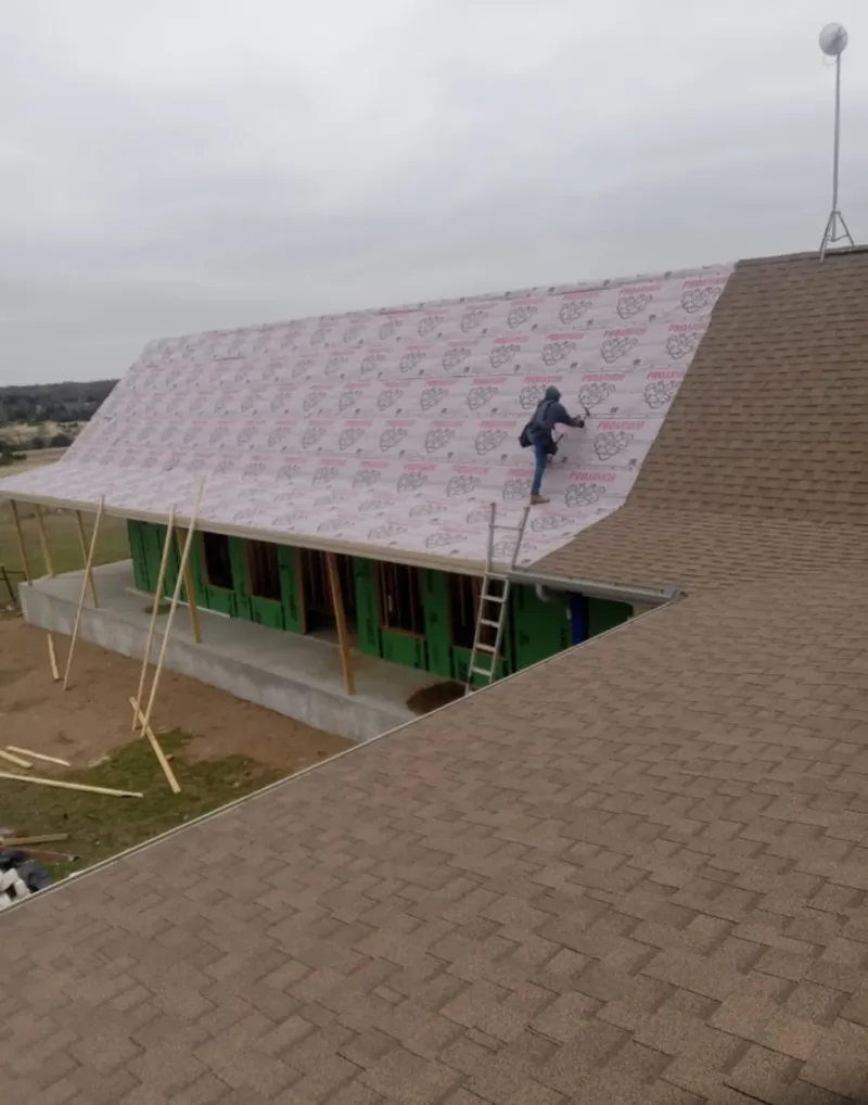Worker preparing underlayment for a metal roof installation in Andrews